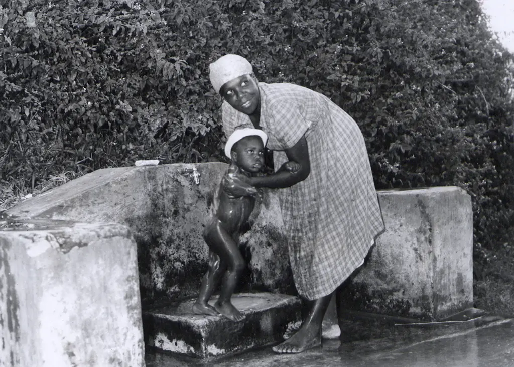 A Barbadian woman bathing her little boy under the communal tap near Bathsheba